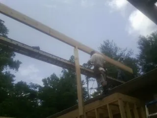 Carpenter setting a ridge beam over a new addition frame — Ice Dam Removal by Roofing Brothers in Colman
