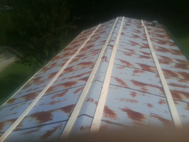 Rusted metal roof panels with new wood purlins before replacement — Storm Damage Roof Repair in Colman by Roofing Brothers