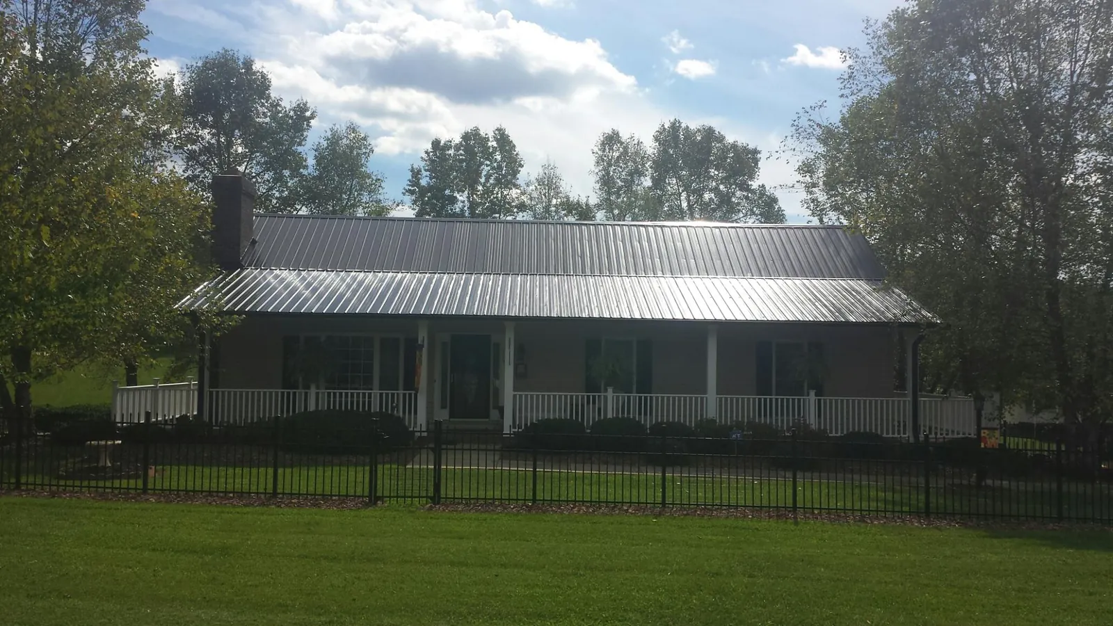 Gray metal roof on a brick ranch with a full width front porch — Gutter Guard Installation work by our crew in Colman