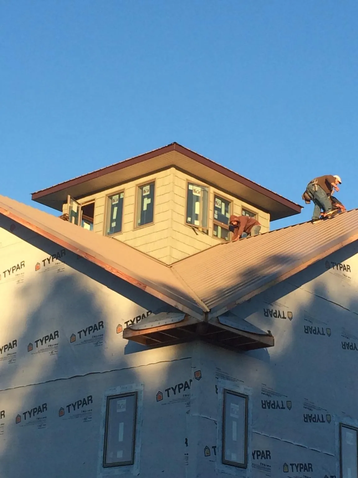 Roofers working around a rooftop cupola on a new metal roof at sunset — Roof Waterproofing in Colman by Roofing Brothers